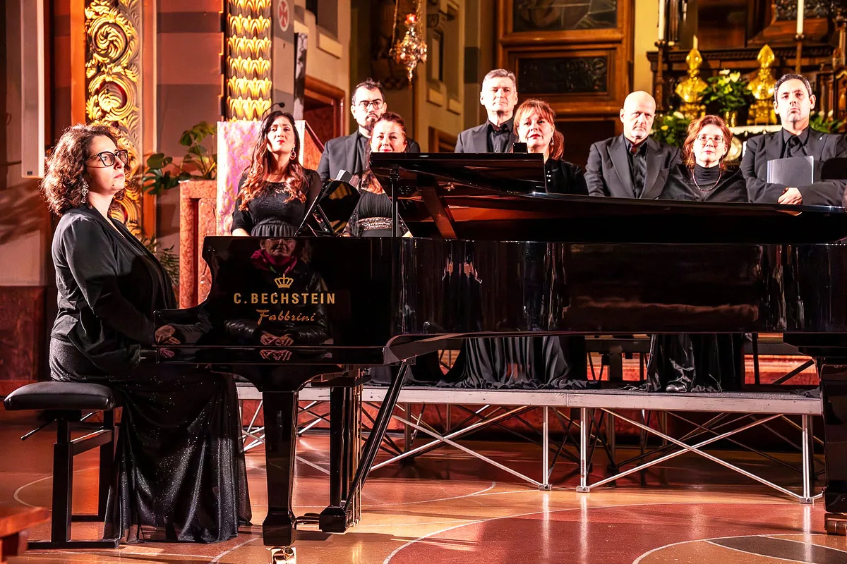 Il coro e la pianista al pianoforte Bechstein in una chiesa illuminata